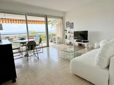 a living room with a white couch and a television at Quiet Flat with view and Swimming pool in Nice