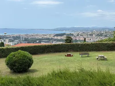 two picnic tables in a park with a view of a city at Quiet Flat with view and Swimming pool in Nice
