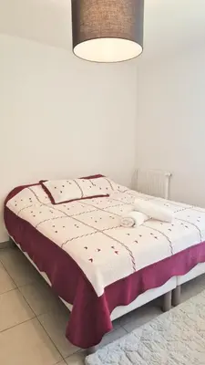 a bed in a white room with a blanket on it at T4 avec grande terrasse - BBQ - parking in La Trinité