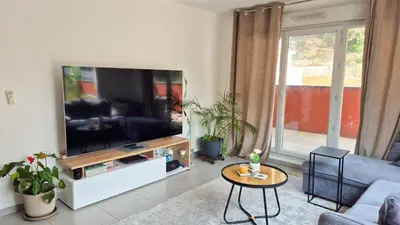 a living room with a large flat screen tv at T4 avec grande terrasse - BBQ - parking in La Trinité