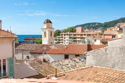 a view of the roofs of a town with a clock tower at #50 Contesso Duplex -1BDR, Sea View Terrace & AC in Villefranche-sur-Mer