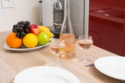 a table with two glasses of wine and a plate of fruit at Perle de Nice - 50 mètres de la plage, Clim, Wifi in Nice