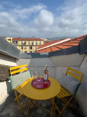 a yellow table with two chairs and a bottle of wine at 1 bedroom, Best location in Nice in Nice