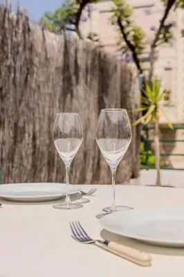 a table with two wine glasses and plates on it at Nice, Studio Grande Terrasse à 2 pas de la promenade in Nice