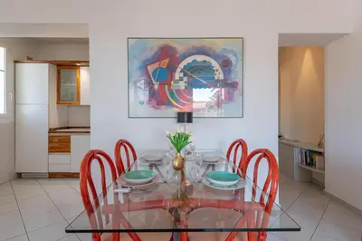 a dining room with a glass table and red chairs at Beaulieu Garden Apartment in Beaulieu-sur-Mer