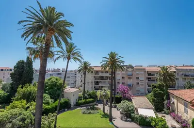 a group of palm trees in front of a building at Beaulieu Garden Apartment in Beaulieu-sur-Mer