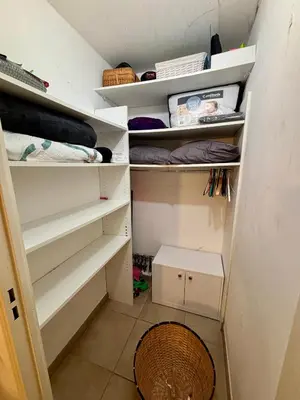 a walk in closet with white shelves and a basket at Magnifique studio avec terrasse et jardin in Nice