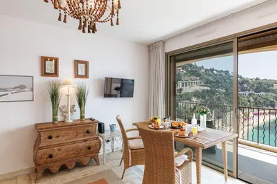 a dining room with a table and a balcony at MY CASA - VILLEFRANCHE RESTANQUES - Panoramic sea view 2 bedrooms Swimming pool in Villefranche-sur-Mer