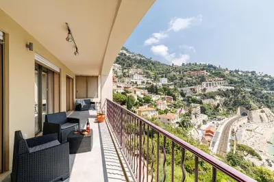a balcony with chairs and a view of a city at MY CASA - VILLEFRANCHE RESTANQUES - Panoramic sea view 2 bedrooms Swimming pool in Villefranche-sur-Mer