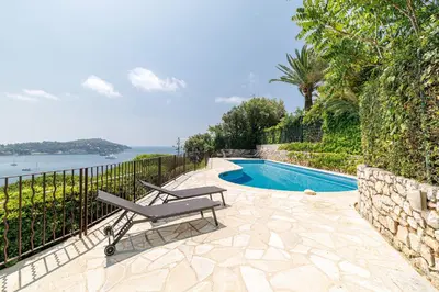 a swimming pool with a chair next to a fence at MY CASA - VILLEFRANCHE RESTANQUES - Panoramic sea view 2 bedrooms Swimming pool in Villefranche-sur-Mer