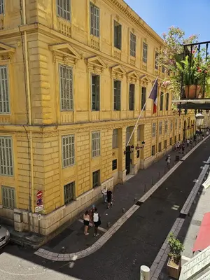 a yellow building with people walking in front of it at Paganini 3bd Apartment in Nice