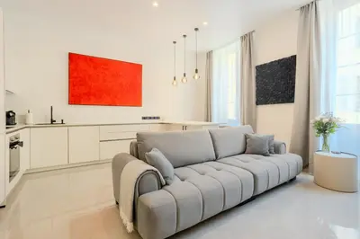 a living room with a couch and a kitchen at Paganini 3bd Apartment in Nice