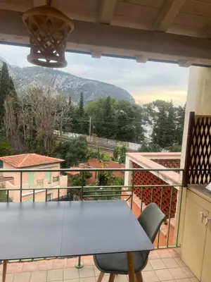 a table on a balcony with a view of a mountain at Cosy studio piscine eze bord de mer in Èze