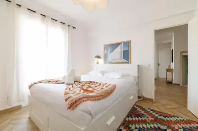 a white bedroom with a large bed and a rug at Wide & Cozy 1 Bdr Downtown in Nice