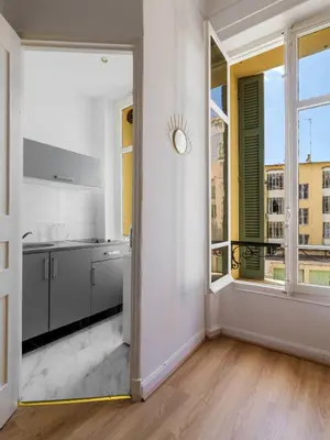 a kitchen with white walls and a large window at Studio cosy dans une belle copropriete classee in Nice