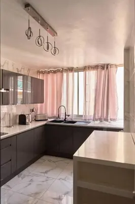 a kitchen with white counters and pink curtains at Appartement 3 pièces Nice-Ouest in Nice