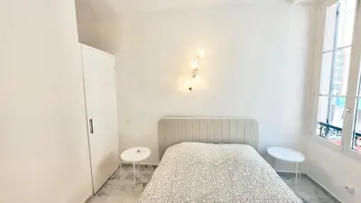 a white bedroom with a bed and two stools at Nest In Nice in Nice