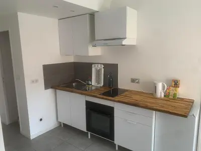 a kitchen with white cabinets and a wooden counter top at studio 30m2 in Nice
