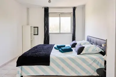 a bedroom with a bed with blue pillows and a window at Appartement Moderne 4 pièces Nice-Ouest in Nice
