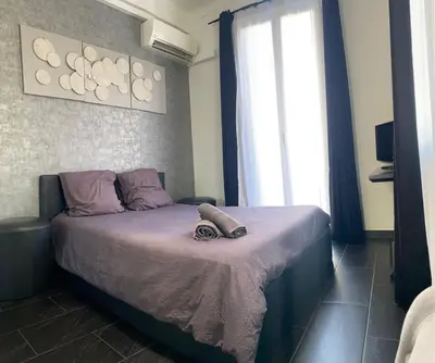 a bedroom with a bed with purple sheets and a window at République in Nice