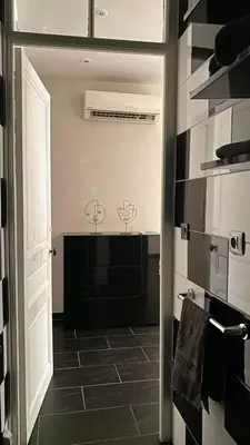a hallway with a door leading to a bathroom with black tiles at République in Nice