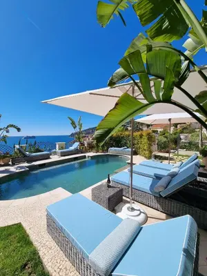 a swimming pool with lounge chairs and an umbrella at Villa Soleil Riviera in Villefranche-sur-Mer