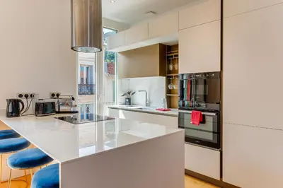 a kitchen with white cabinets and blue stools at 33 MARINONI AP4438 by Riviera Holiday Homes in Beaulieu-sur-Mer