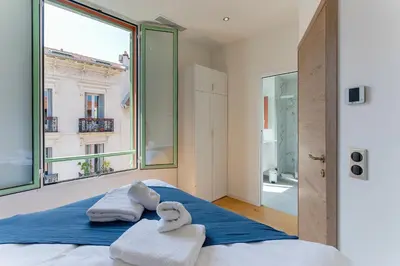 a bedroom with towels on a bed with a large window at 33 MARINONI AP4438 by Riviera Holiday Homes in Beaulieu-sur-Mer