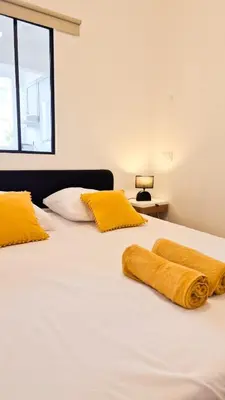 a white bed with two yellow pillows on it at Superbe appartement 3P neuf - terrasse - barbecue in Nice