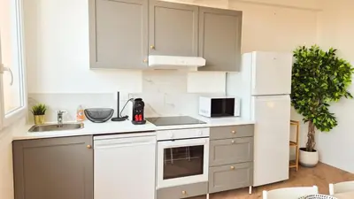 a kitchen with white cabinets and a white refrigerator at Superbe appartement 3P neuf - terrasse - barbecue in Nice