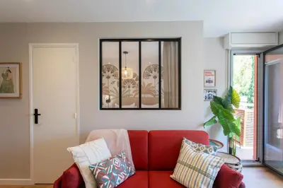 a living room with a red couch and a mirror at Appartement cosy lumineux avec balcon in Nice