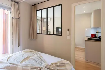a bedroom with a bed and a window and a kitchen at Appartement cosy lumineux avec balcon in Nice