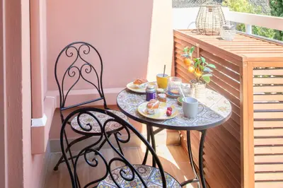 a table and two chairs on a balcony with food on it at Appartement cosy lumineux avec balcon in Nice