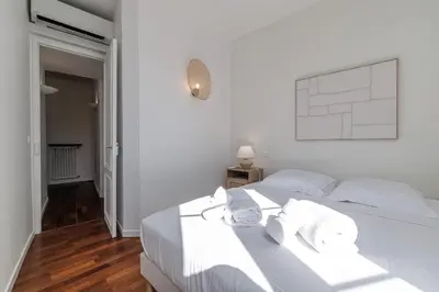 a white bedroom with a bed and a flat screen tv at Wide 1 Bdr Quiet Area Open View in Nice