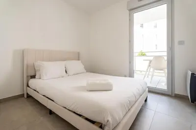 a bedroom with a white bed with a large window at Le Bô Mont in Nice