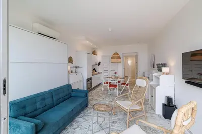 a living room with a blue couch and a kitchen at Sea View & Terrace Promenade des Anglais in Nice