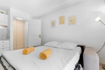 a white bedroom with a bed with yellow towels on it at Le Seaside - Beach - Tram - Airport - AC in Nice