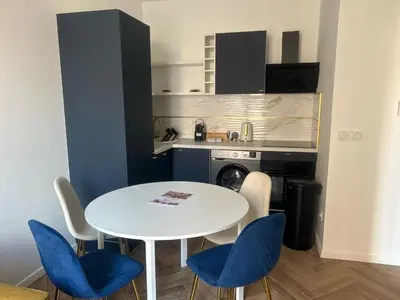 a kitchen with a white table and blue chairs at MOON - 31 in Nice