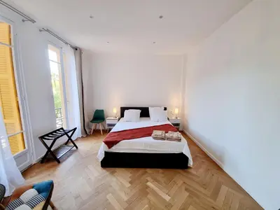 a white bedroom with a bed and two windows at Spacious Family Apartment Near Sea - Nice in Nice