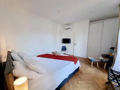 a bedroom with a large white bed with a red blanket at Spacious Family Apartment Near Sea - Nice in Nice