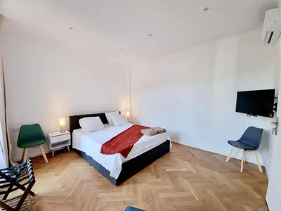 a bedroom with a bed and two chairs and a television at Spacious Family Apartment Near Sea - Nice in Nice