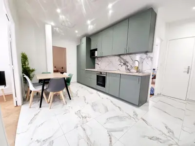a kitchen with green cabinets and a table with chairs at Spacious Family Apartment Near Sea - Nice in Nice
