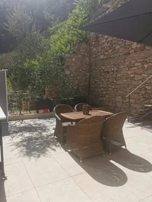 a wooden table with chairs and an umbrella on a patio at Villa Ninette avec rooftop in Villefranche-sur-Mer