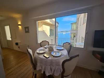 a dining room with a table and a large window at Villa Ninette avec rooftop in Villefranche-sur-Mer