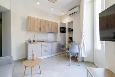 a kitchen with white cabinets and a table and chairs at T2 situé au centre-ville de Nice in Nice