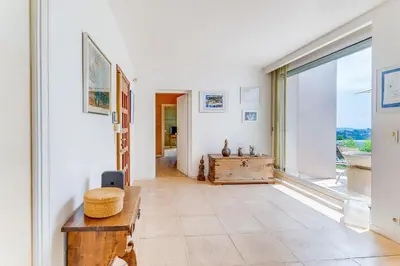 a hallway with a table and a large window at VILLA DYONIS VI4439 by Riviera Holiday Homes in Nice