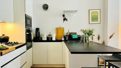 a kitchen with white cabinets and a black counter top at Bel appartement 2 pièces à Nice in Nice