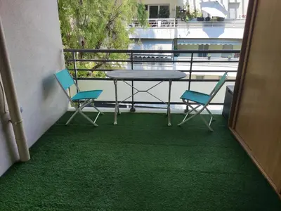 a table and chairs on a balcony with green carpet at Appartement deux pièces bien situé et pratique in Nice