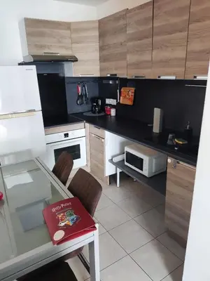 a kitchen with a glass table and a microwave at Appartement deux pièces bien situé et pratique in Nice