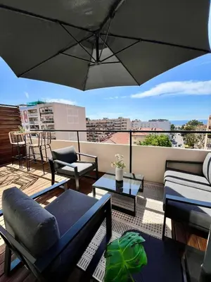 a rooftop patio with an umbrella and chairs and tables at TheNiceTerrace in Nice